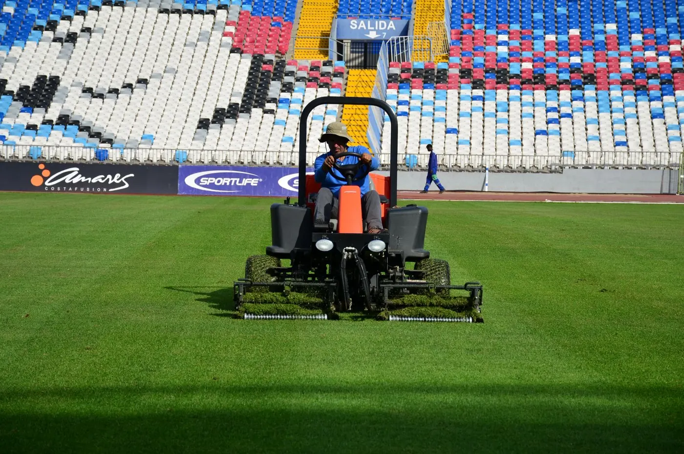 Mantención de cancha de fútbol con segadora en un estadio