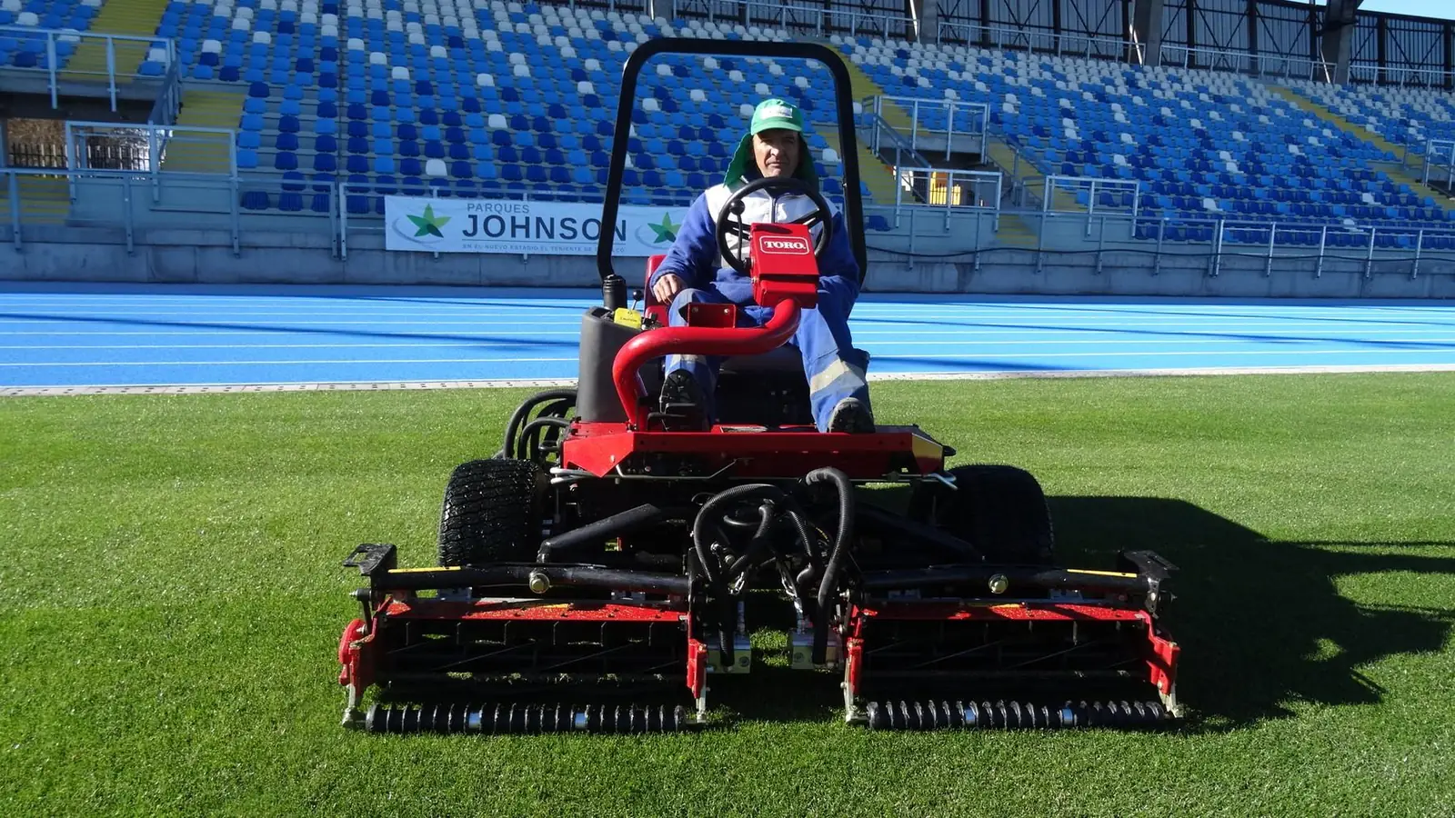 Operario de Parques Johnson con segadora en un estadio